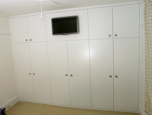Fitted wardrobe with flush handles and TV