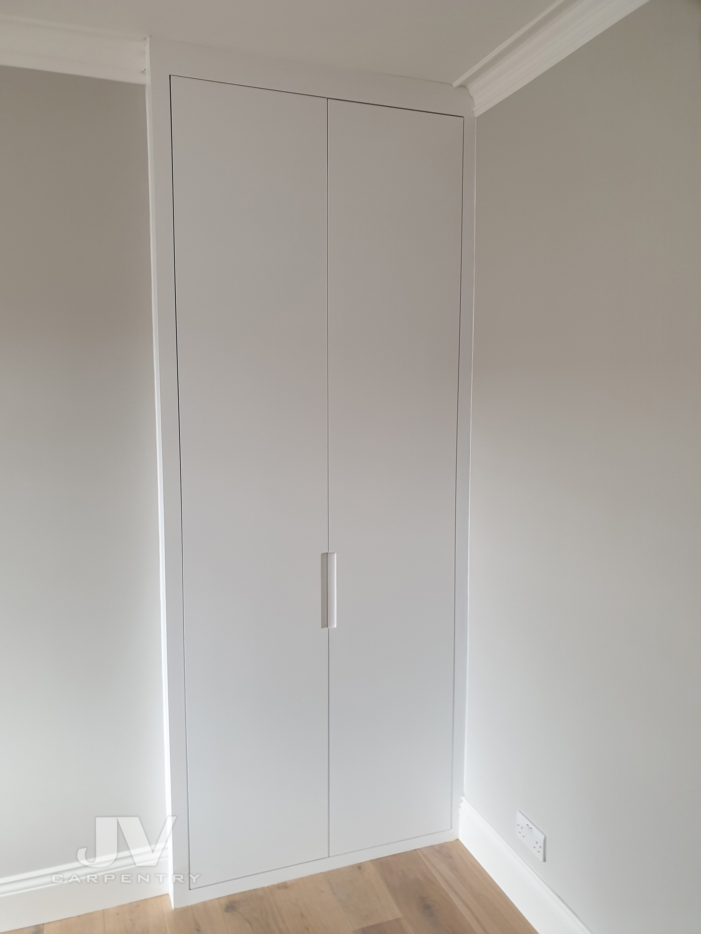 Fitted alcove wardrobe with plain doors