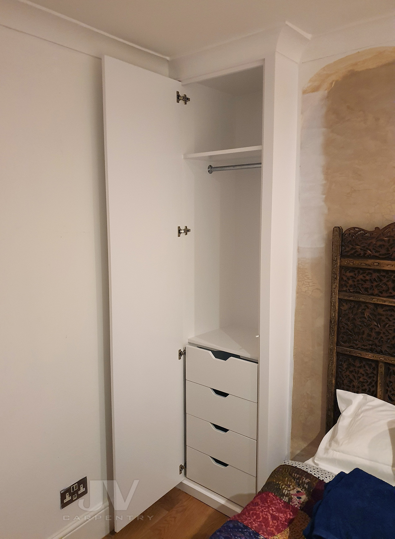 Small wardrobe by bed with open door