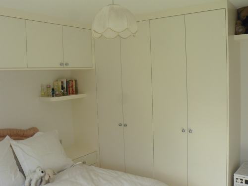 plain wardrobe with shelves and cupboards above the bed