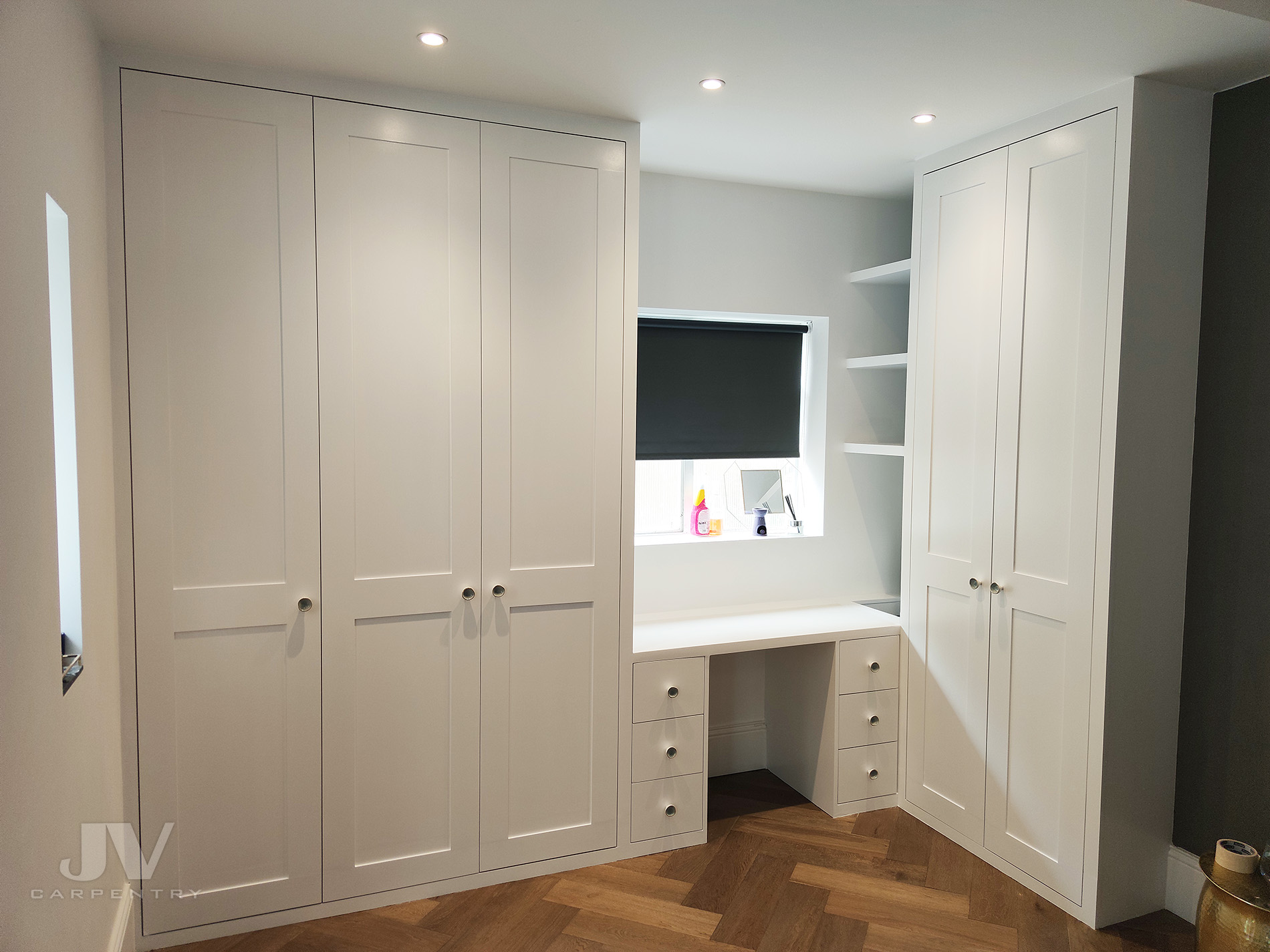 Fitted wardrobe built around window with dressing table